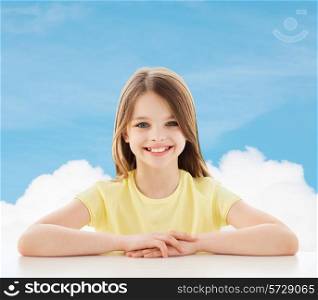 childhood, happiness and people concept - beautiful little girl sitting at table over blue sky background