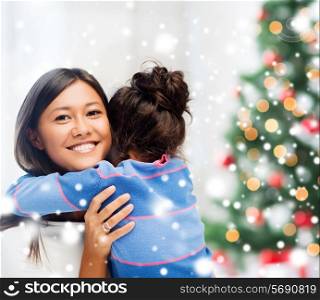 childhood, happiness, christmas, family and people concept - smiling little girl and mother hugging indoors