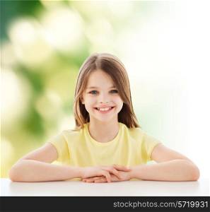childhood, happiness, ecology and people concept - beautiful little girl sitting at table over green background