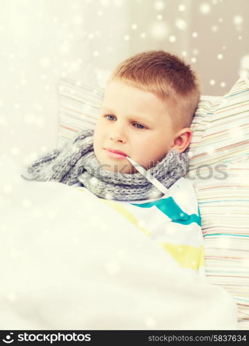 childhood, healthcare and medicine concept - ill boy with thermometer lying in bed and measuring temperature at home