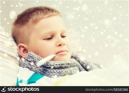 childhood, healthcare and medicine concept - ill boy with thermometer lying in bed and measuring temperature at home