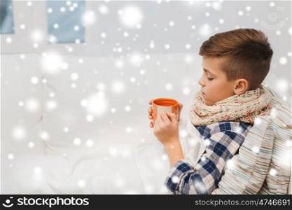 childhood, healthcare, people and medicine concept - ill boy with flu lying in bed and drinking tea at home over snow