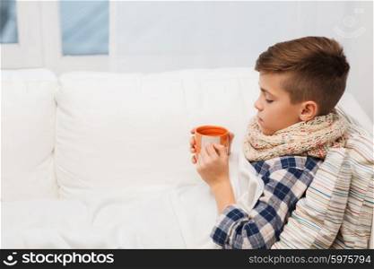 childhood, healthcare, people and medicine concept - ill boy with flu lying in bed and drinking tea at home