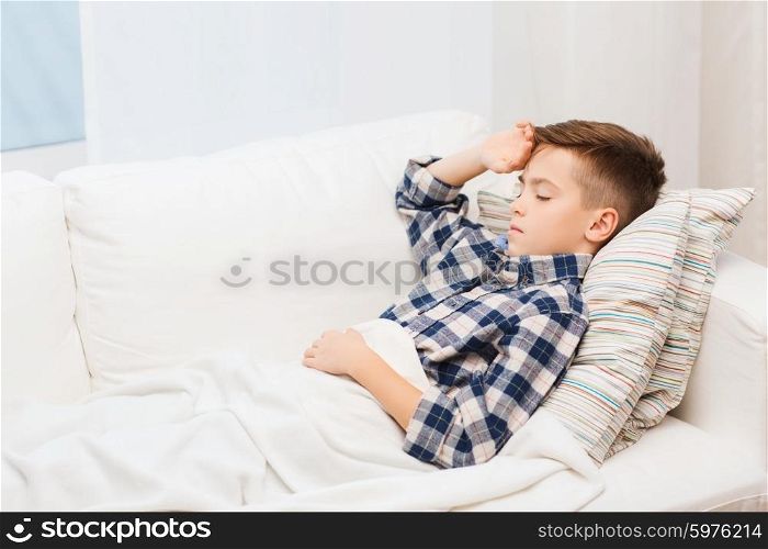 childhood, healthcare, people and medicine concept - ill boy with flu lying in bed at home and suffering from headache