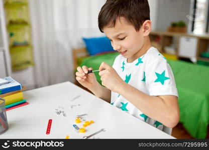 childhood, hobby and leisure concept - little boy playing with building kit at home. little boy playing with building kit at home