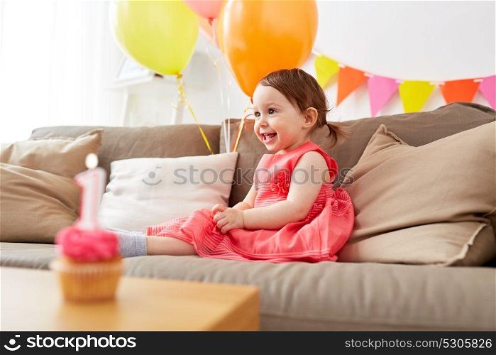 childhood, holidays and people concept - happy baby girl air balloons and garland on birthday party at home. happy baby girl on birthday party at home