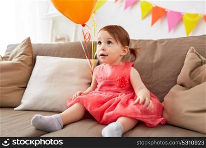 childhood, holidays and people concept - happy baby girl on birthday party at home. happy baby girl on birthday party at home