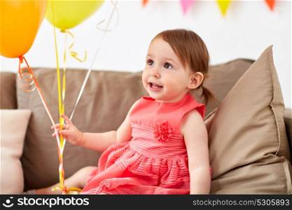 childhood, holidays and people concept - happy baby girl with air balloons on birthday party at home. happy baby girl on birthday party at home