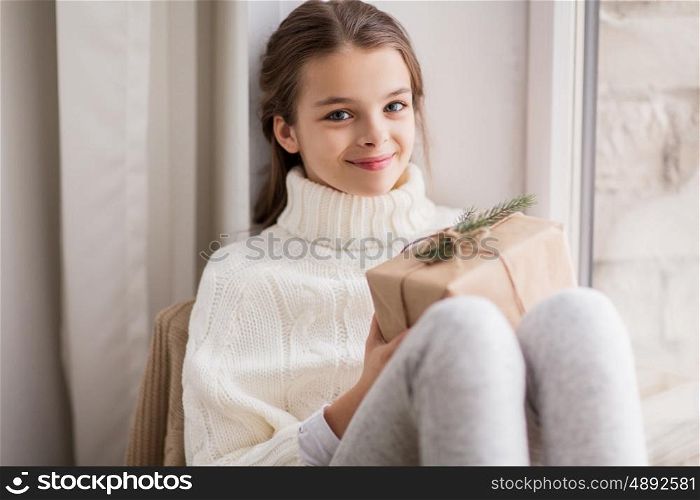 childhood, holidays and people concept - happy beautiful girl with christmas gift sitting at home
