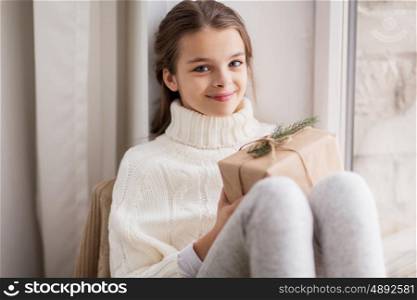 childhood, holidays and people concept - happy beautiful girl with christmas gift sitting at home