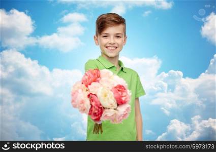 childhood, holidays and people concept - happy boy holding flower bunch over blue sky and clouds background