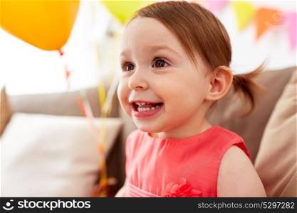 childhood, holidays, emotions and people concept - happy baby girl on birthday party at home. happy baby girl on birthday party at home