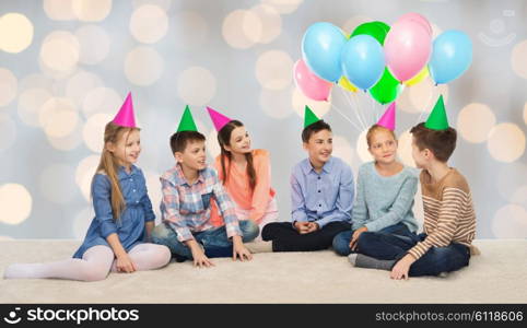 childhood, holidays, friendship and people concept - happy smiling children in party hats on birthday over lights background