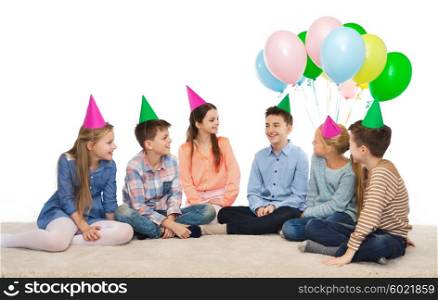 childhood, holidays, friendship and people concept - happy smiling children in party hats on birthday