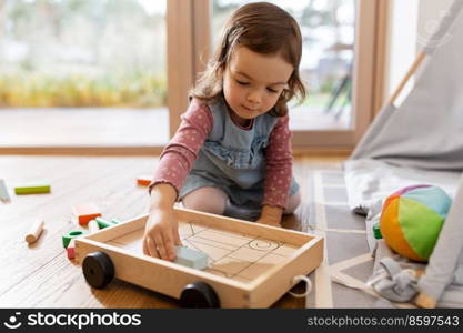 childhood, hygge and people concept - little baby girl playing with toy blocks at home. happy baby girl playing with toy blocks at home