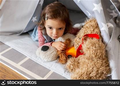 childhood, hygge and people concept - little baby girl playing with toys in kid&rsquo;s tent or teepee at home. baby girl playing with toys in or teepee at home