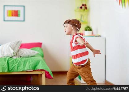 childhood, imagination and dream concept - happy little boy in pilot hat playing game at home. happy little boy in pilot hat playing at home