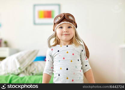 childhood, imagination and dream concept - happy little girl in pilot hat playing game at home. happy little girl in pilot hat playing at home