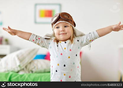 childhood, imagination and dream concept - happy little girl in pilot hat playing game at home. happy little girl in pilot hat playing at home