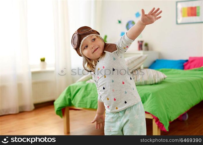 childhood, imagination and dream concept - happy little girl in pilot hat playing game at home. happy little girl in pilot hat playing at home
