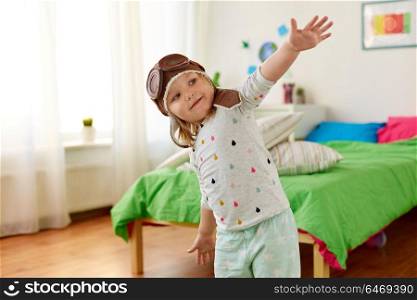 childhood, imagination and dream concept - happy little girl in pilot hat playing game at home. happy little girl in pilot hat playing at home