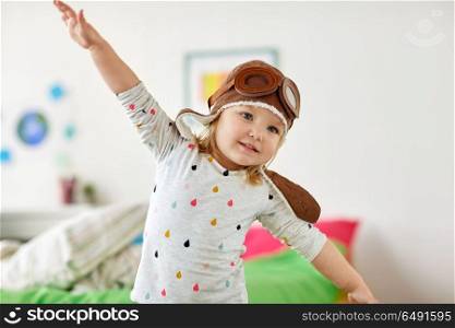 childhood, imagination and dream concept - happy little girl in pilot hat playing game at home. happy little girl in pilot hat playing at home. happy little girl in pilot hat playing at home