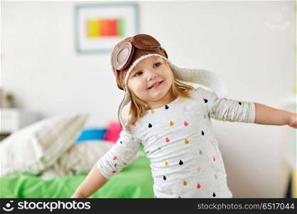 childhood, imagination and dream concept - happy little girl in pilot hat playing game at home. happy little girl in pilot hat playing at home. happy little girl in pilot hat playing at home