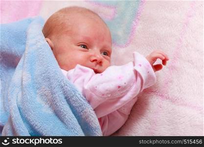 Childhood innocence concept. Little adorable newborn baby lying on bed with many blankets.. Little newborn baby lying in blanket