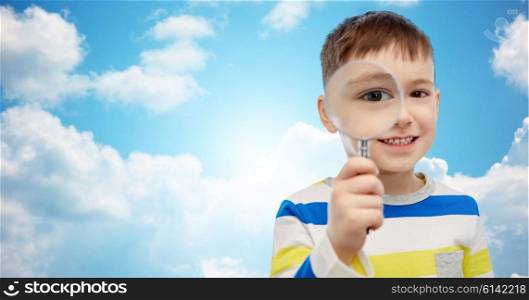 childhood, investigation, discovery, vision and people concept - happy little boy looking through magnifying glass over blue sky and clouds background