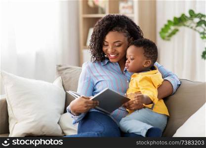 childhood, kids and people concept - happy african american mother with book and her baby son at home. african american mother with book and baby at home