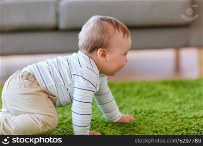 childhood, kids and people concept - lovely baby boy crawling on floor at home. baby boy crawling on floor at home