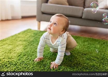 childhood, kids and people concept - lovely baby boy playing with soap bubbles at home. baby boy playing with soap bubbles at home