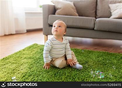 childhood, kids and people concept - lovely baby boy playing with soap bubbles at home. baby boy playing with soap bubbles at home