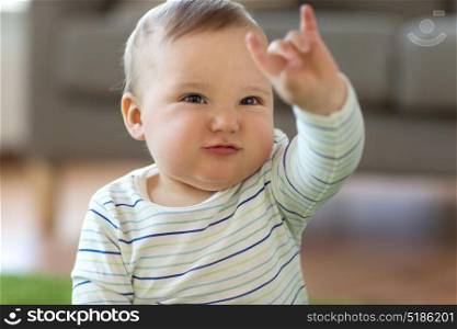 childhood, kids and people concept - lovely baby boy showing rock hand sign at home. baby boy showing rock hand sign at home