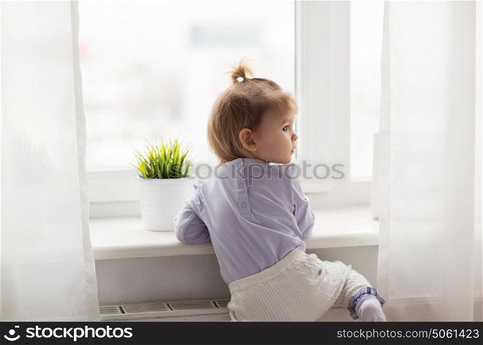 childhood, kids and people concept - lovely little girl at home window. lovely little girl at home window