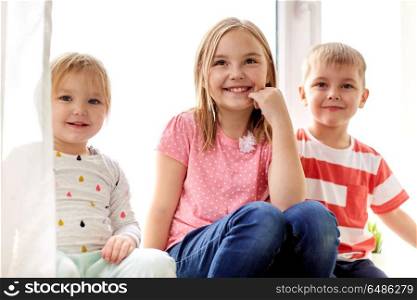 childhood, leisure and family concept - happy little kids having fun at window. happy little kids having fun at window. happy little kids having fun at window
