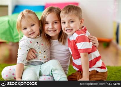 childhood, leisure and family concept - happy little kids hugging at home. happy little kids hugging at home. happy little kids hugging at home