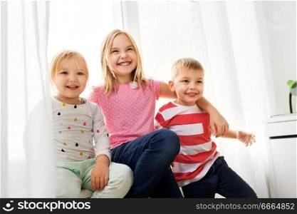 childhood, leisure and family concept - happy little kids hugging at window. happy little kids hugging at window