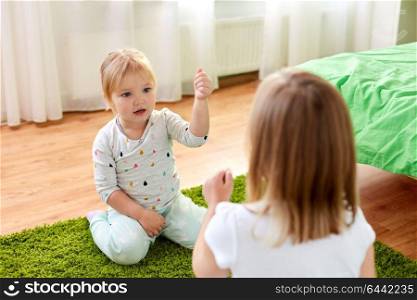 childhood, leisure and family concept - little girls playing rock-paper-scissors game at home. girls playing rock-paper-scissors game at home