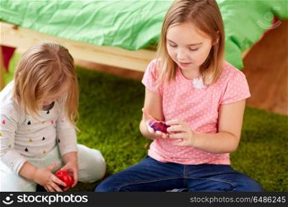 childhood, leisure and people concept - girls or sisters with modelling clay or slimes at home. sisters with modelling clay or slimes at home. sisters with modelling clay or slimes at home