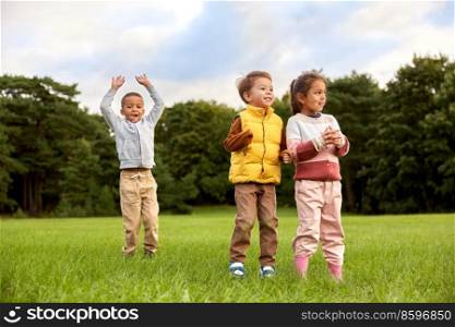 childhood, leisure and people concept - group of happy children playing and jumping at park. happy children playing and jumping at park