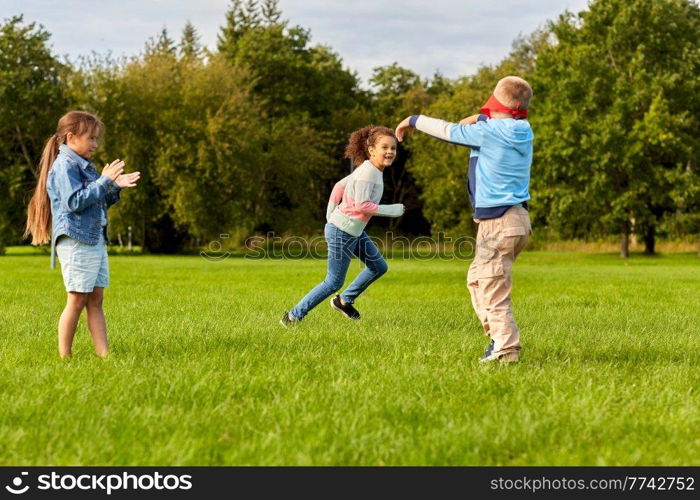 childhood, leisure and people concept - group of happy children playing tag game and running at park. happy children playing and running at park