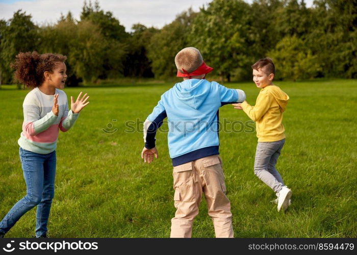 childhood, leisure and people concept - group of happy children playing tag game and running at park. happy children playing and running at park