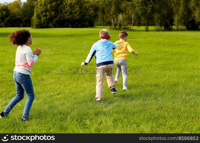 childhood, leisure and people concept - group of happy children playing tag game and running at park. happy children playing and running at park