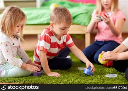 childhood, leisure and people concept - group of happy kids and and mother with modelling clay or slimes at home. kids and mother with modelling clay or slimes. kids and mother with modelling clay or slimes