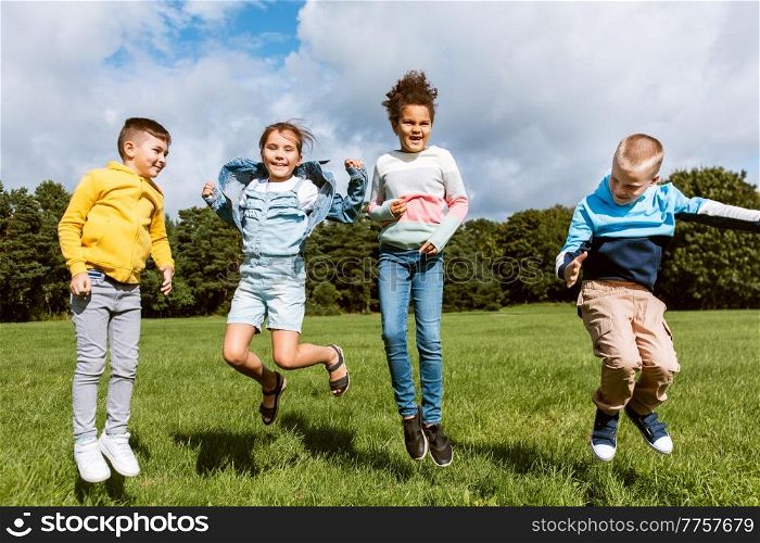 childhood, leisure and people concept - group of happy kids jumping and having fun at park. happy children jumping and having fun at park
