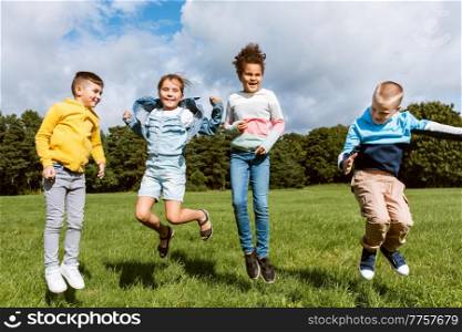 childhood, leisure and people concept - group of happy kids jumping and having fun at park. happy children jumping and having fun at park
