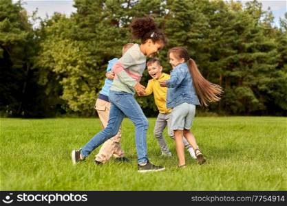 childhood, leisure and people concept - group of happy kids playing and having fun at park. happy children playing and having fun at park