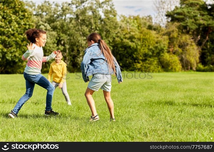 childhood, leisure and people concept - group of happy kids playing tag game and running at park. happy children playing and running at park