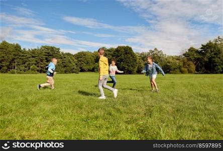 childhood, leisure and people concept - group of happy kids playing tag game and running at park. happy children playing and running at park